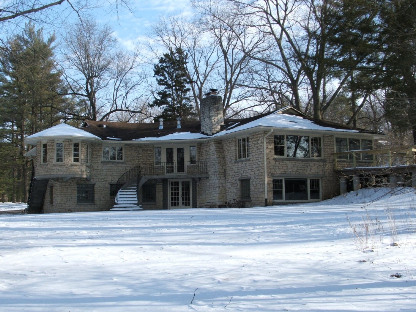 A snow-covered stone house in Iowa City with an integrated exterior wheelchair ramp visible at right.
