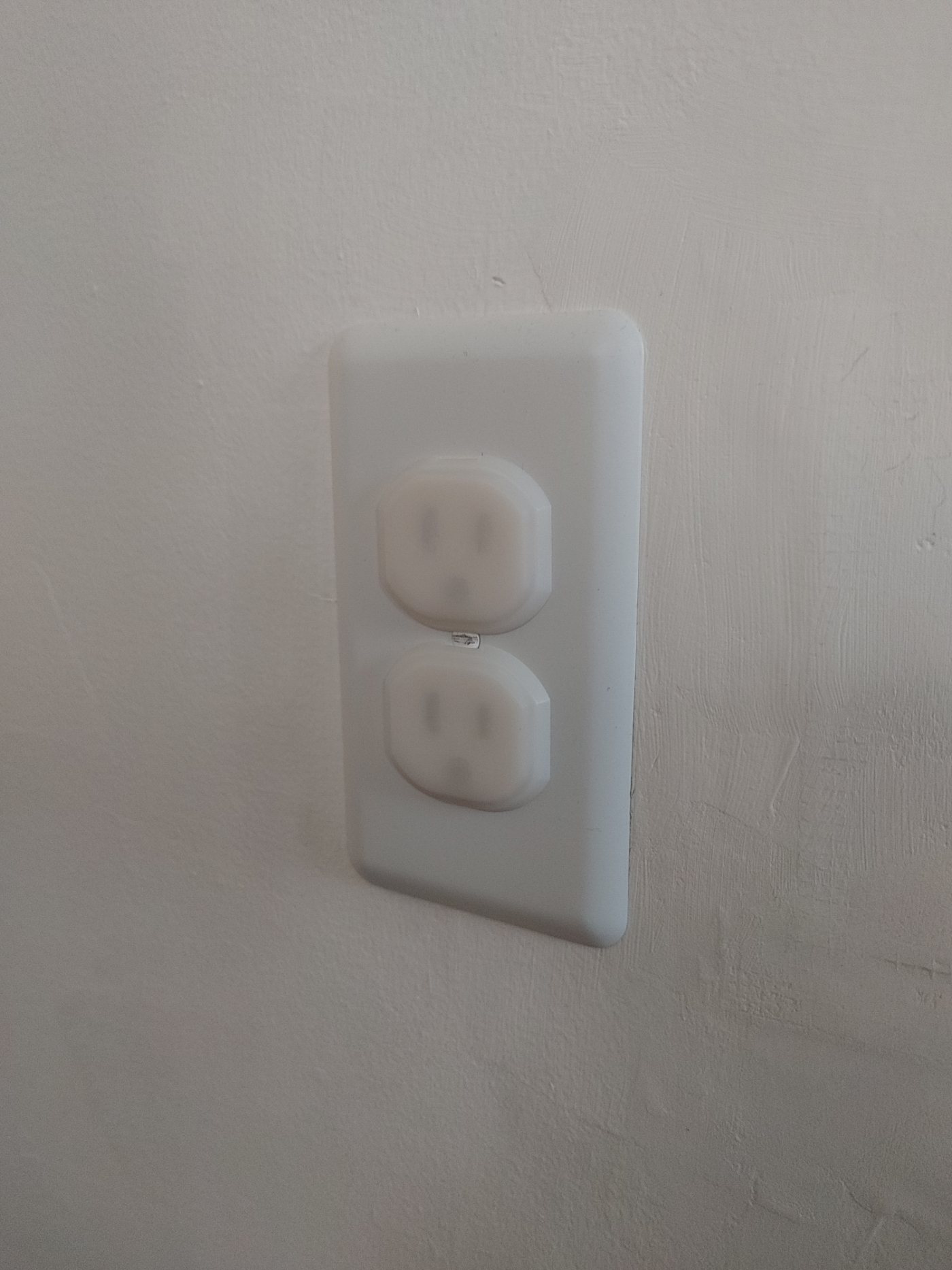 Wall electrical outlet fitted with two white plastic outlet safety covers