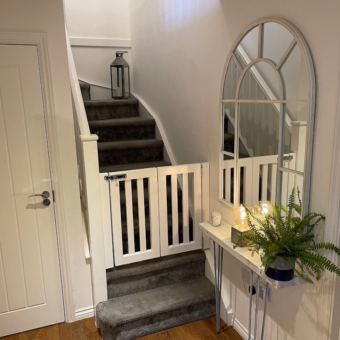 White child safety gate installed across a carpeted staircase in a home