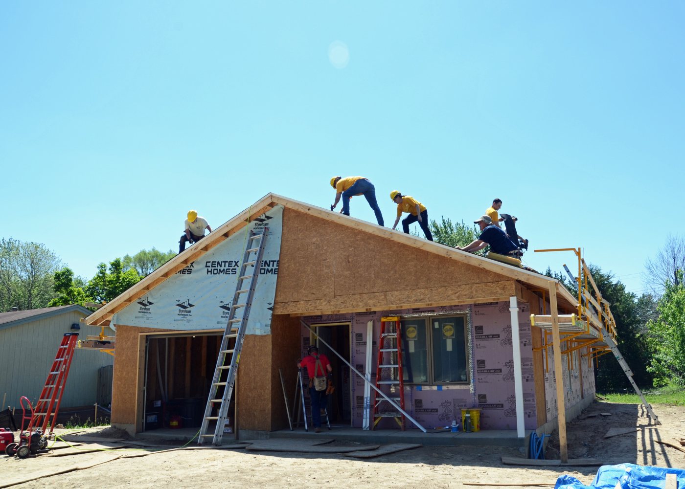 Volunteers wearing safety helmets work on the roof of a partially constructed house in Machesney Park, Illinois.