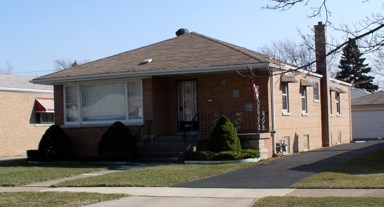 Brick Chicago bungalow with a detached garage and front lawn.