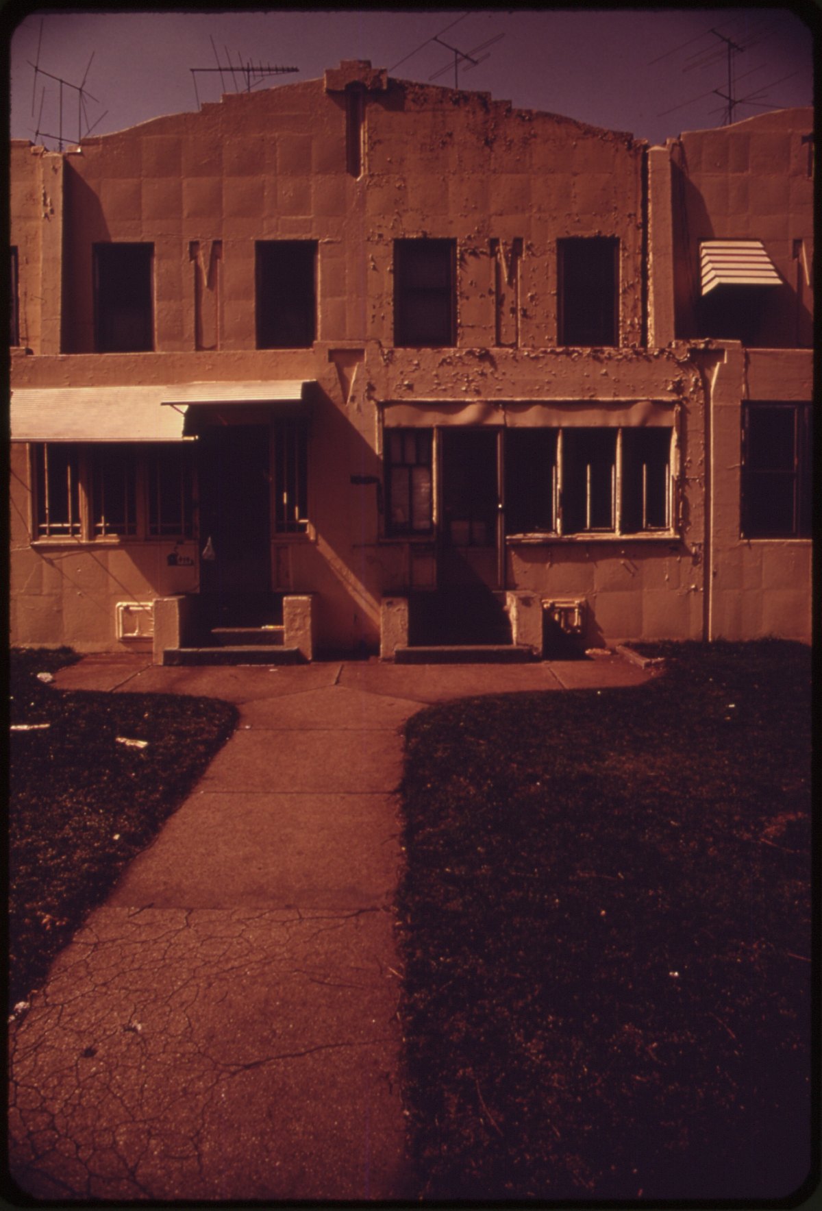 Older row house in Gary, Indiana, with extensive peeling and deteriorated exterior paint.