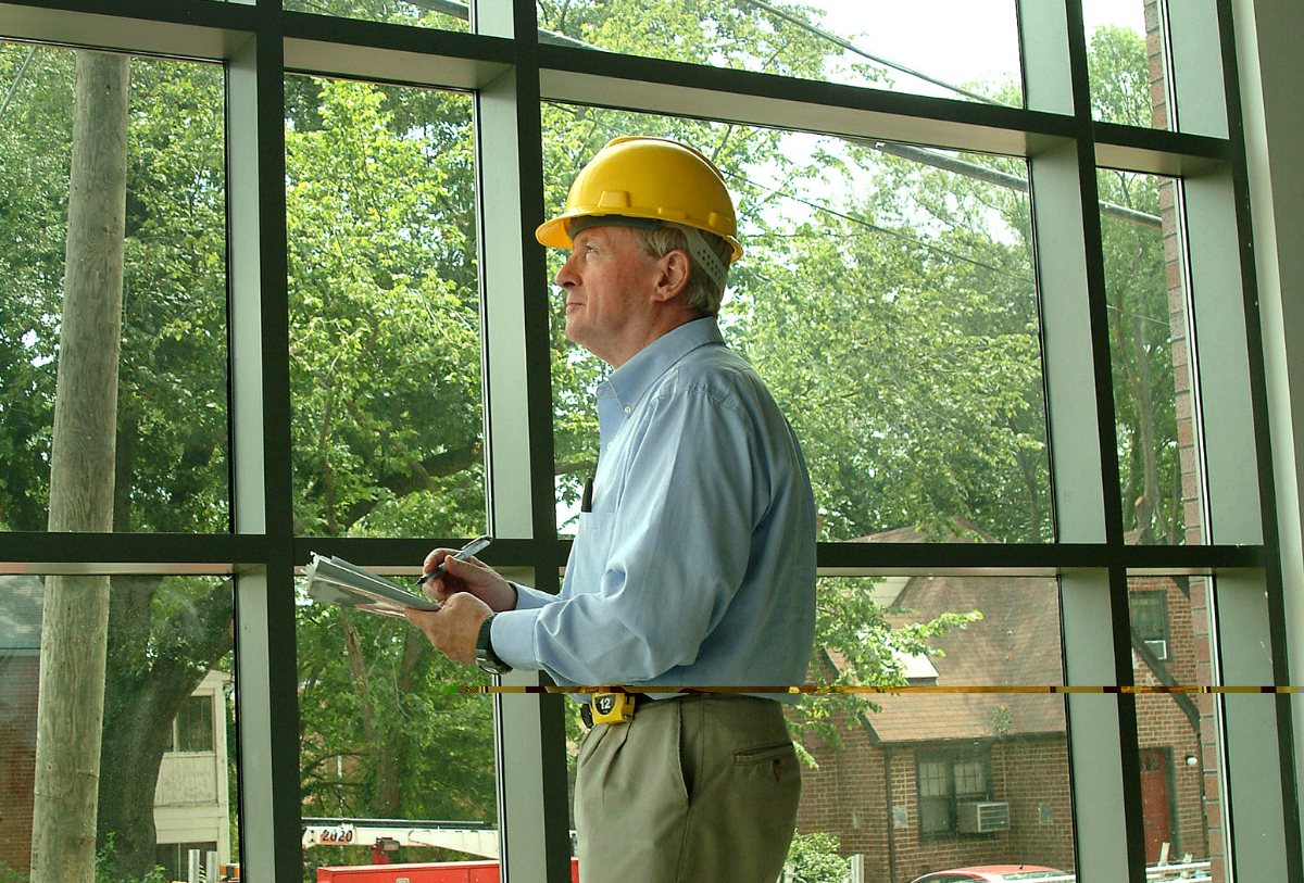 Building inspector wearing a hard hat takes notes during an interior construction inspection.