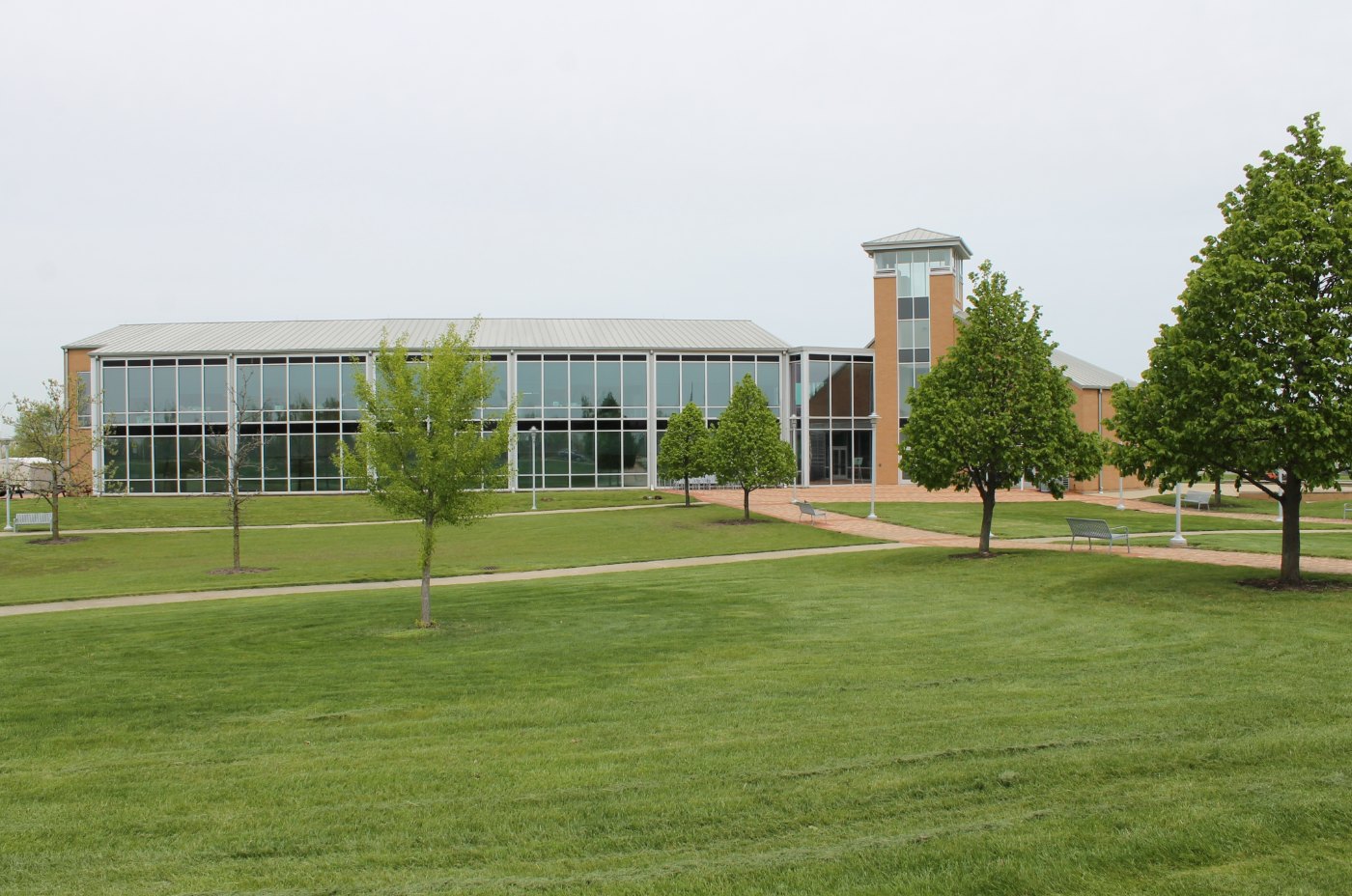 Modern Matteson Village Hall with a glass-fronted wing, brick tower, lawn, and trees in Matteson, Illinois.
