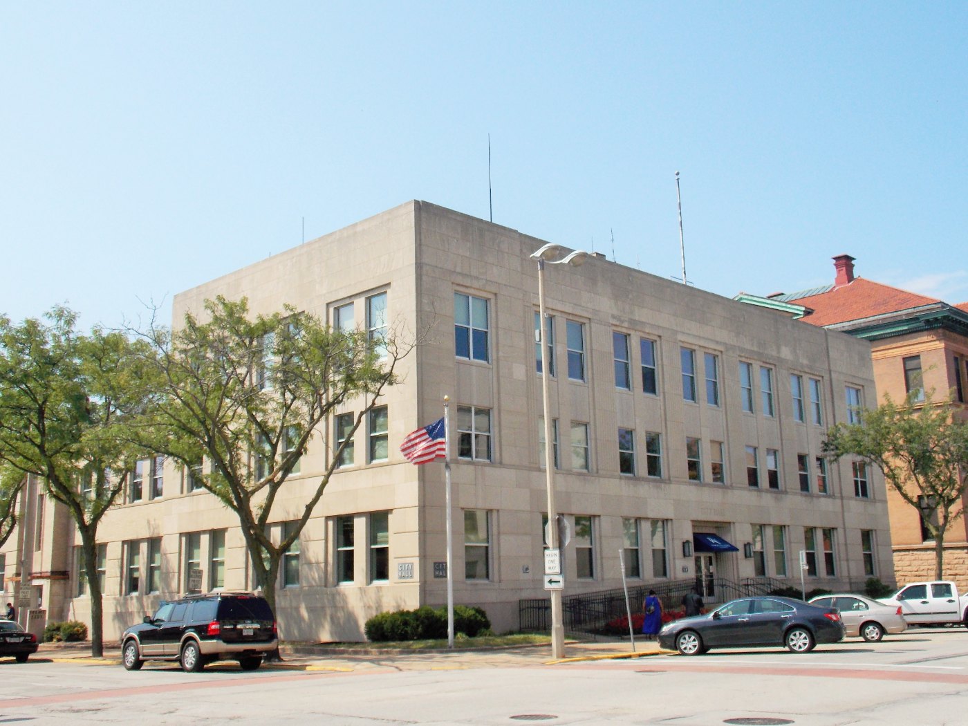 Street-level exterior of Rock Island City Hall with flagpoles at the municipal entrance in Rock Island, Illinois.